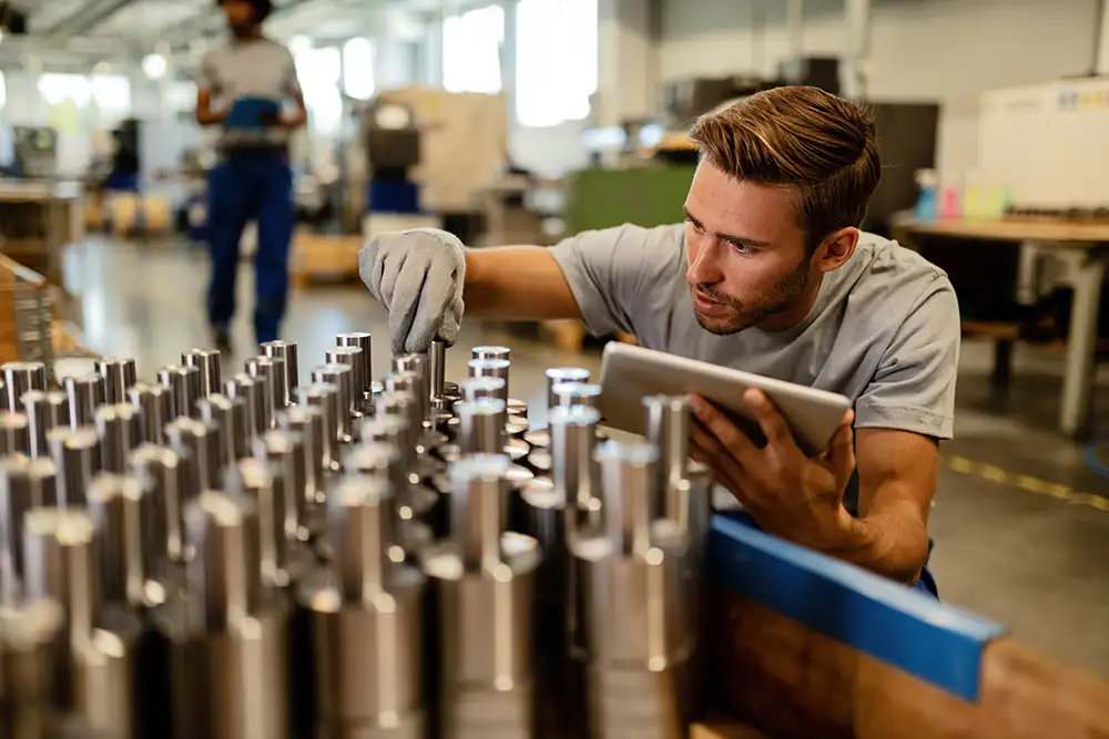 Worker using a tablet to inspect precision-manufactured parts